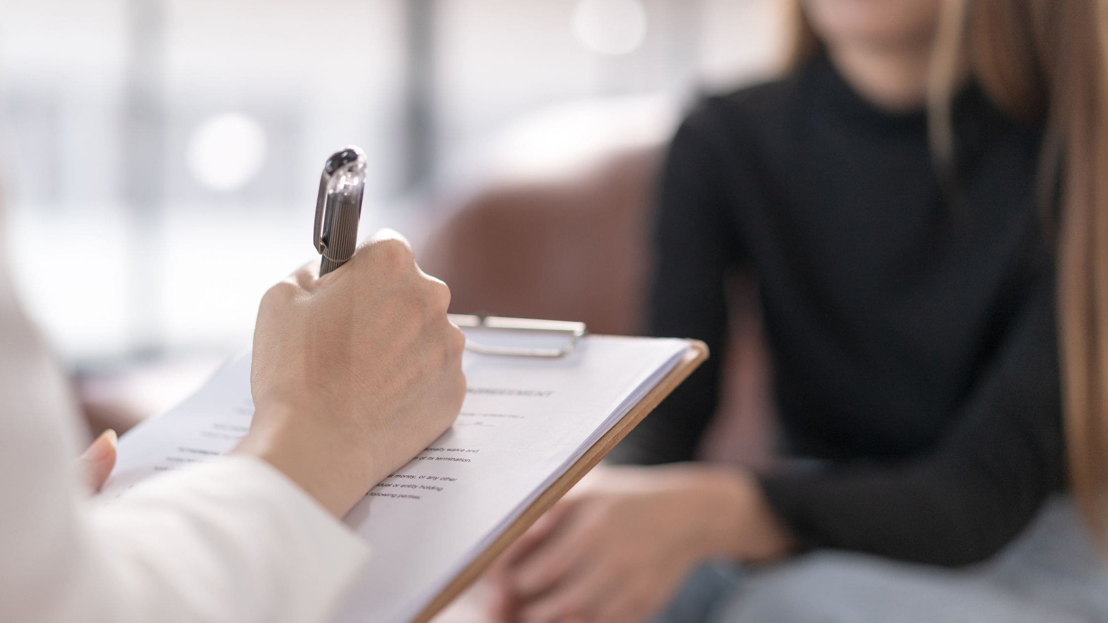 Professionista che prende appunti durante un colloquio psicologico